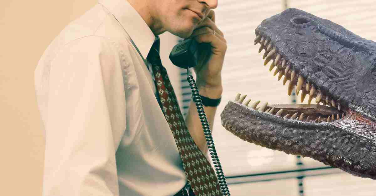 Mężczyzna rozmawia przez ztary telefon i widzi dinozaura