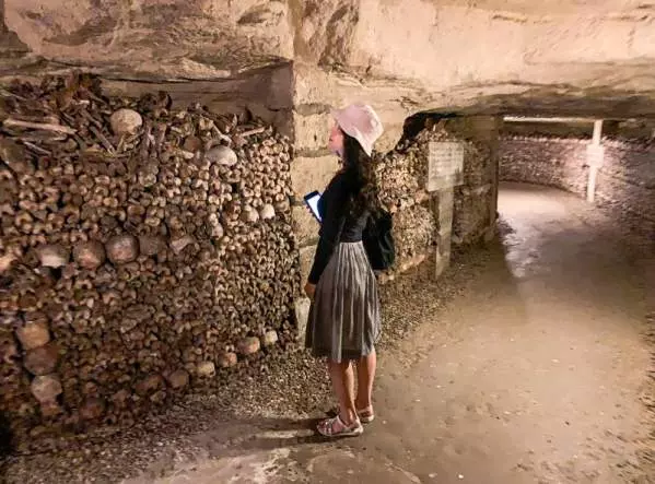 Kobieta podziwia ludzkie kości w jednej z publicznie dostępnych przestrzeni paryskich katakumb