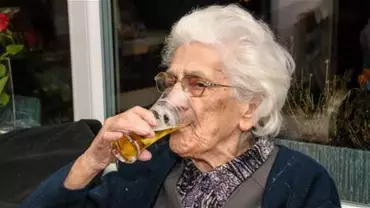 Starsza kobieta pije piwo