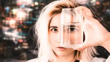Kobieta patrzy przez szklankę z wodą - Widzimy świat przez filtr własnych doświadczeń